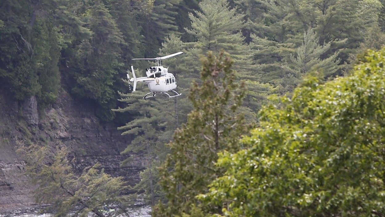 Un hélicoptère de la Sûreté du Québec survolant une rivière.