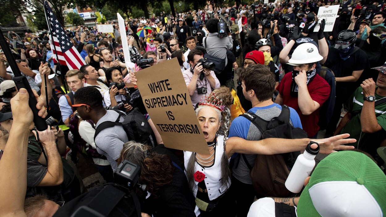 Au milieu de la foule, une manifestante tient une pancarte sur laquelle on peut lire : Â« Le suprÃ©macisme blanc est du terrorisme Â». 