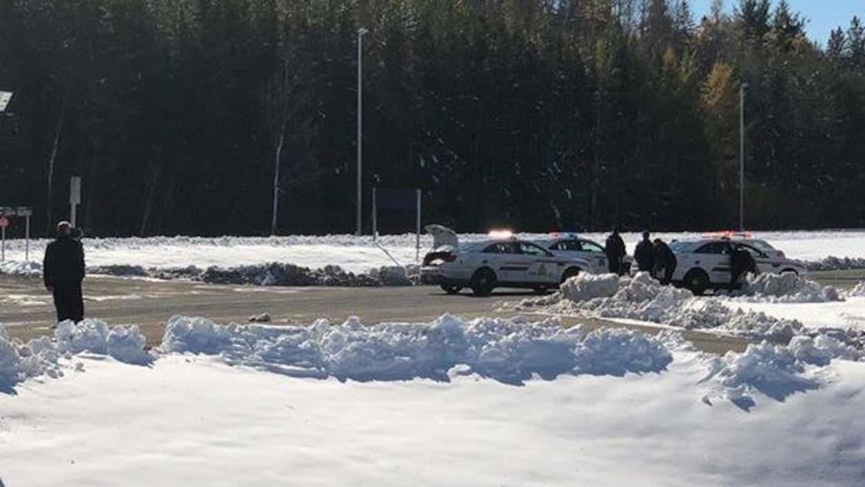 Des policiers debout autour de trois véhicules de patrouille