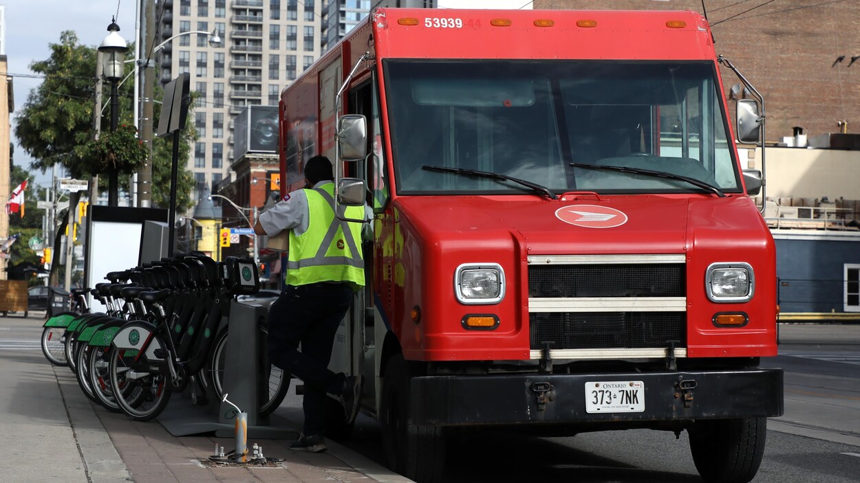 Un employé de Postes Canada descend d'une fourgonnette.
