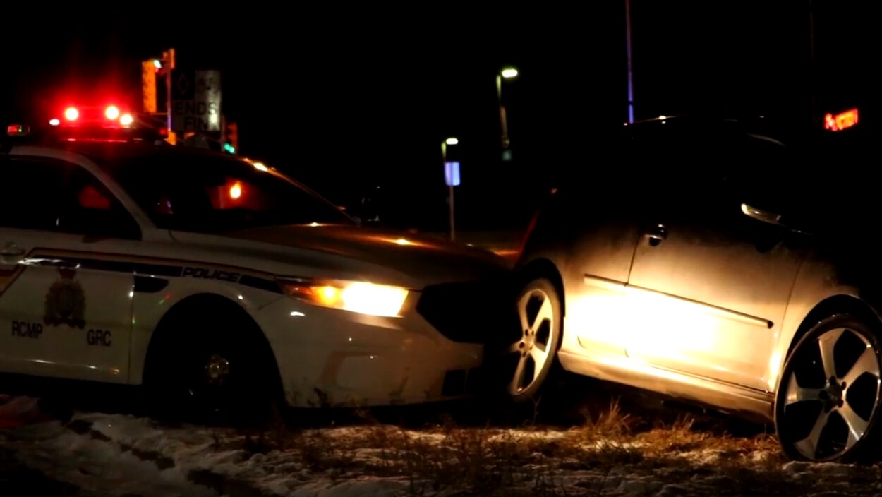 Photo prise de nuit d'une Jetta en bordure de la route, emboutie par une voiture de la GRC.