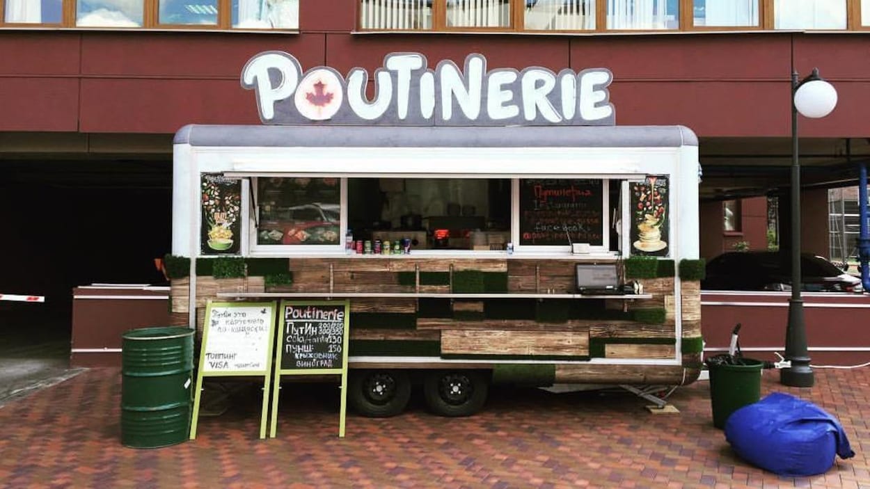 Une roulotte avec l'inscription « Poutinerie » est stationnée devant un bâtiment. Une roulotte avec l'inscription « Poutinerie » est stationnée devant un bâtiment.