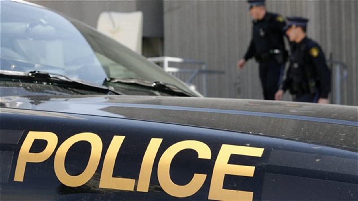 Une voiture de police avec des agents en arrière-plan.