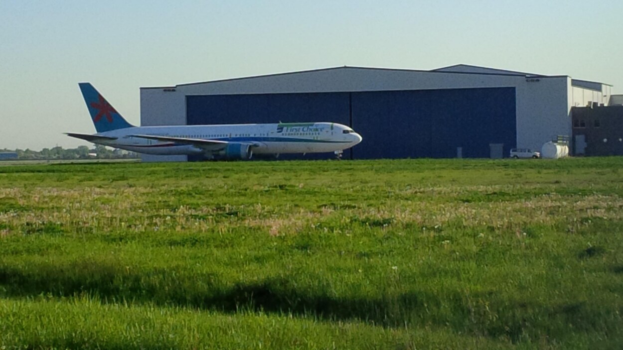 Un avion devant un hangar.