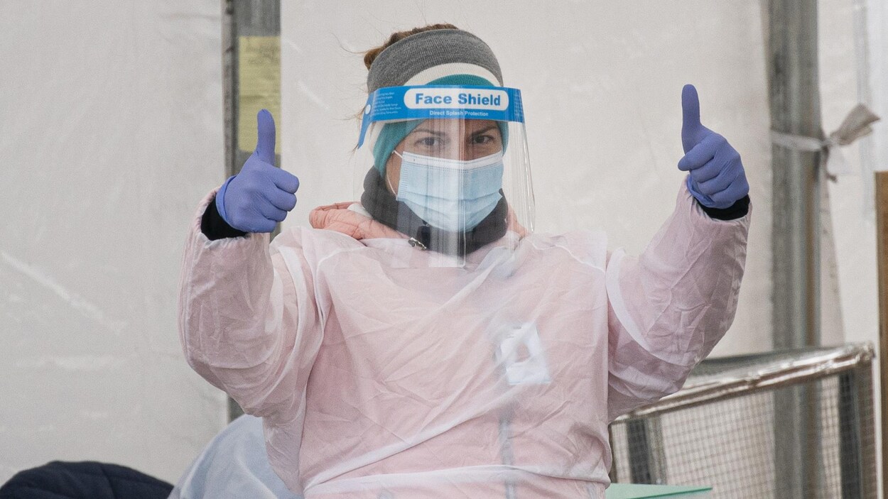 Une préposée de la santé avec son masque et sa combinaison lève les deux pouces.