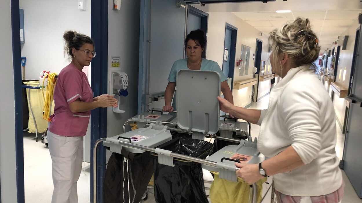 Des préposées aux bénéficiaires autour d'un chariot dans un corridor.