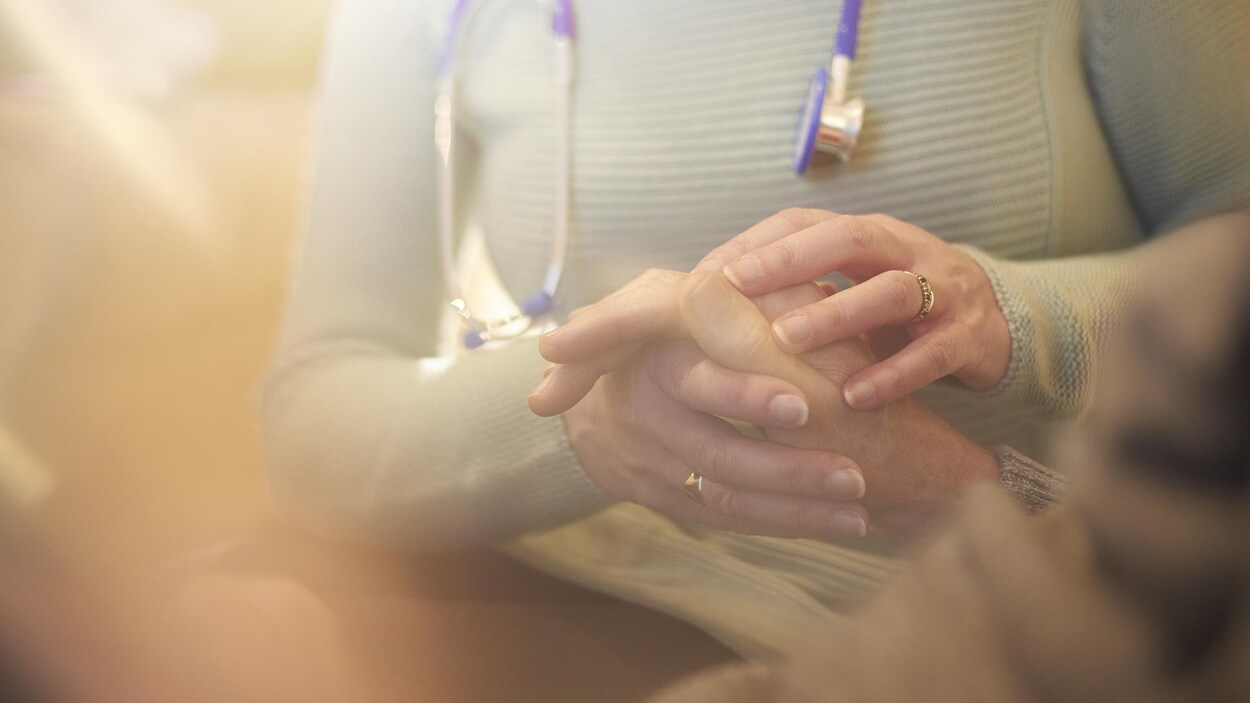 Un professionnel de la santé tient la main d'une personne âgée.
