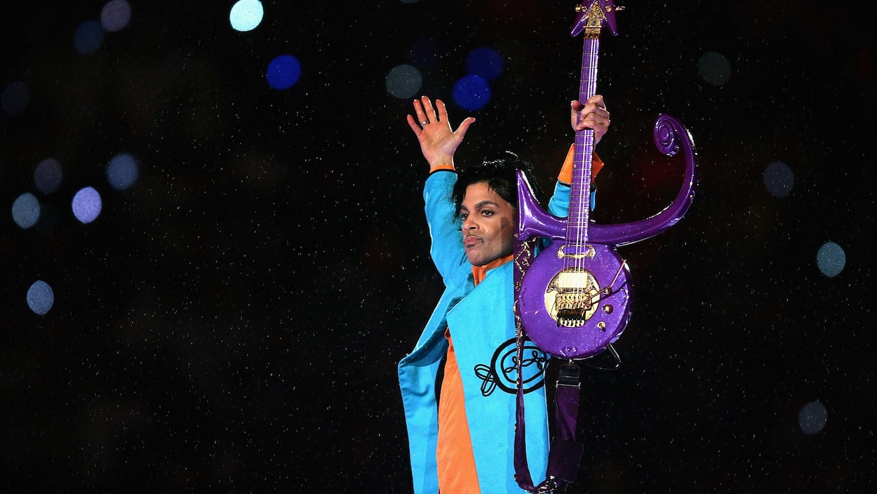 Prince en costume bleu brandit sa guitare