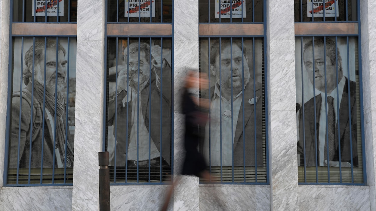 Une femme passe devant des affiches sur lesquelles on voit des photos des dirigeants catalans Jordi Cuixart, Jordi Sanchez, Oriol Junqueras et Joaquim Forn.