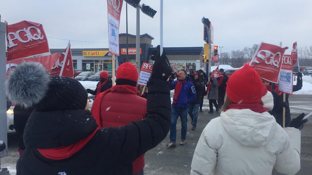 Des employés qui manifestent pancarte à la main.