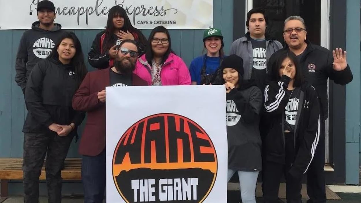 Un groupe de personnes tenant une grande affiche devant un café.