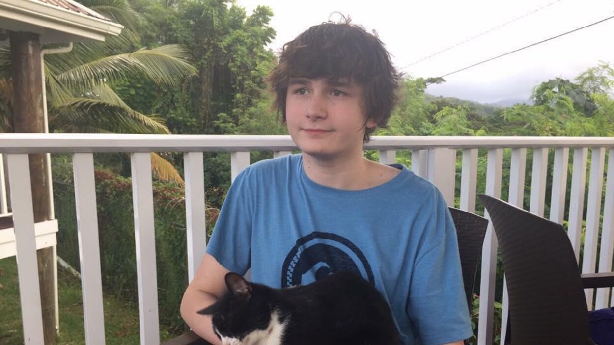 Matthew regarde au loin, un chat assis sur ses genoux.