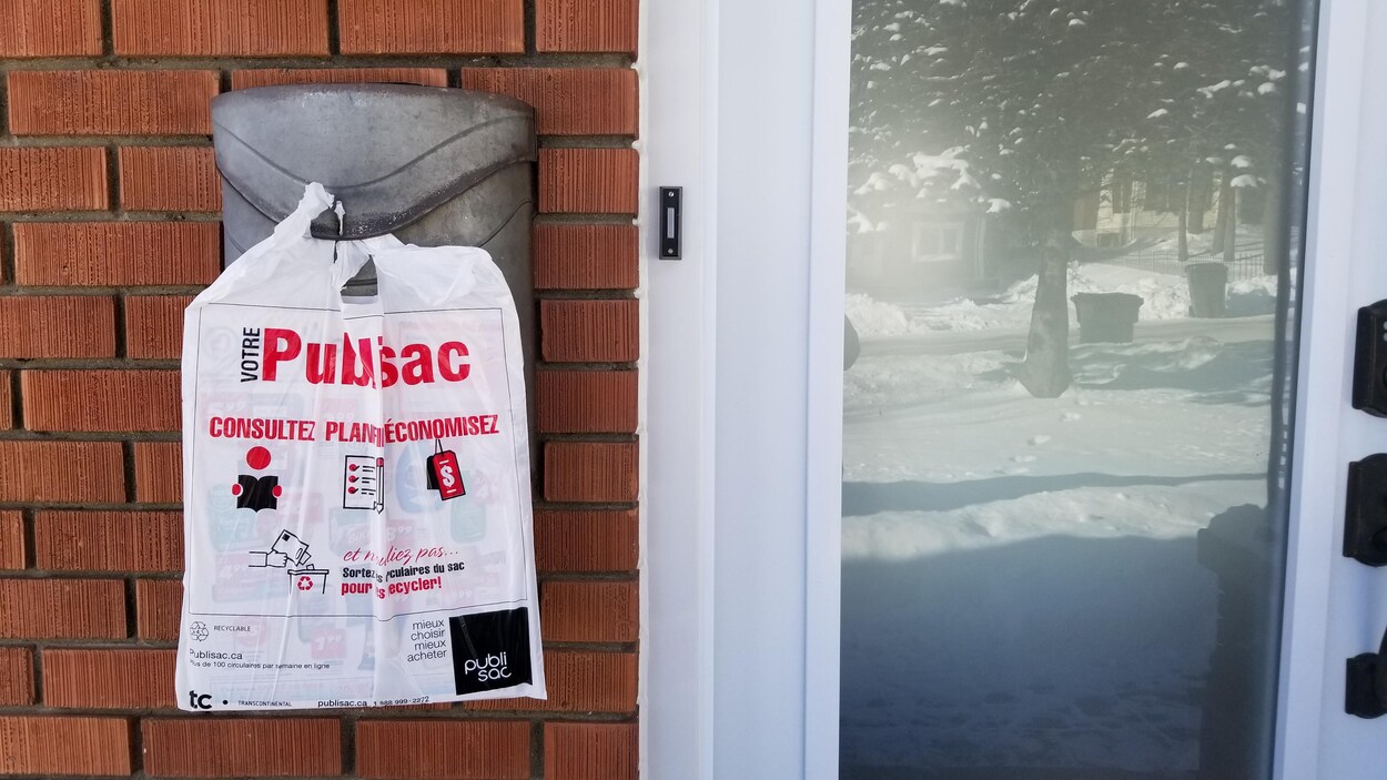 Un Publisac accroché à une boîte aux lettres devant une maison.