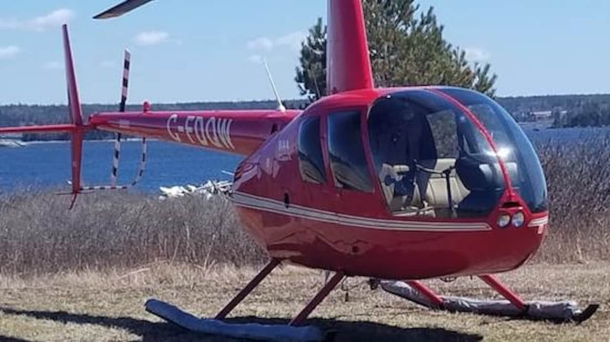 Un petit hélicoptère rouge immobile dans la cour.