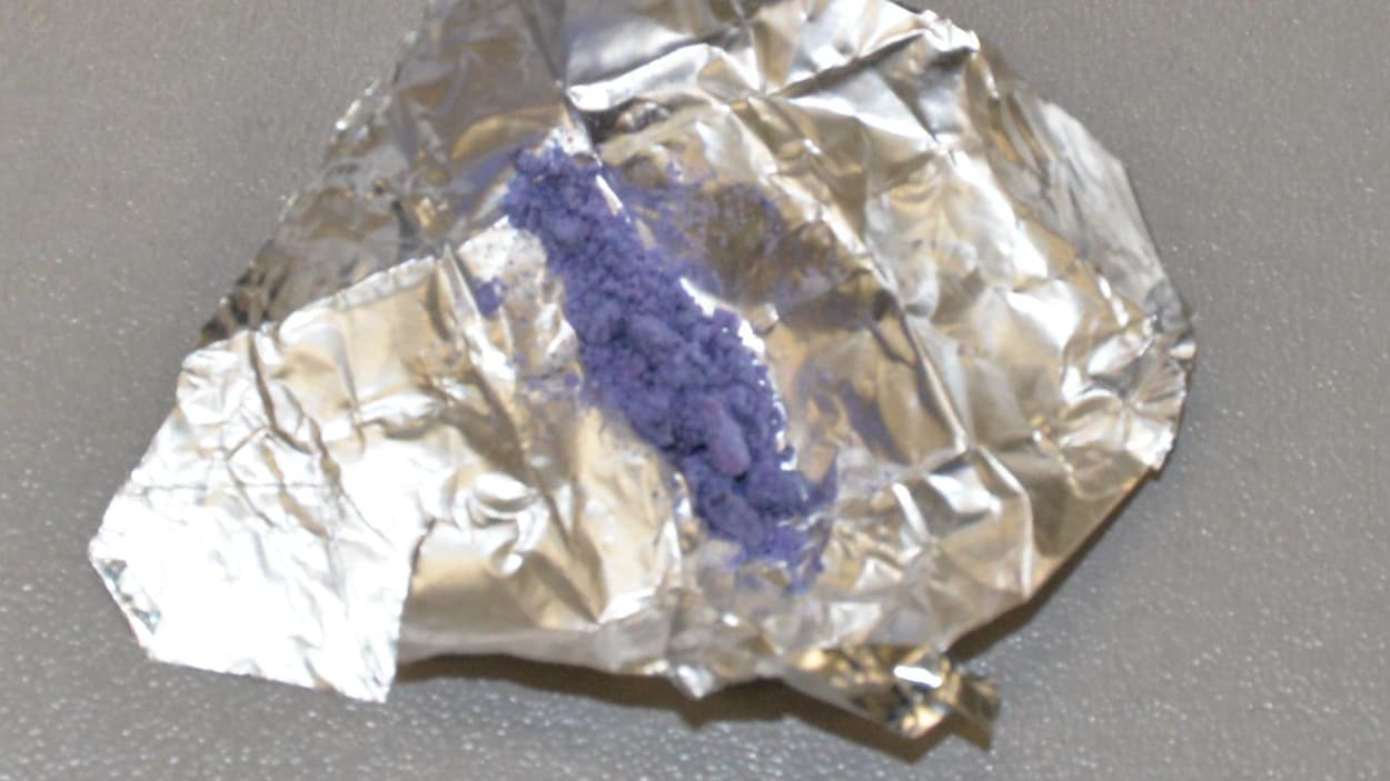 Une poudre violette déborde d’un sachet d'héroïne entrouvert.