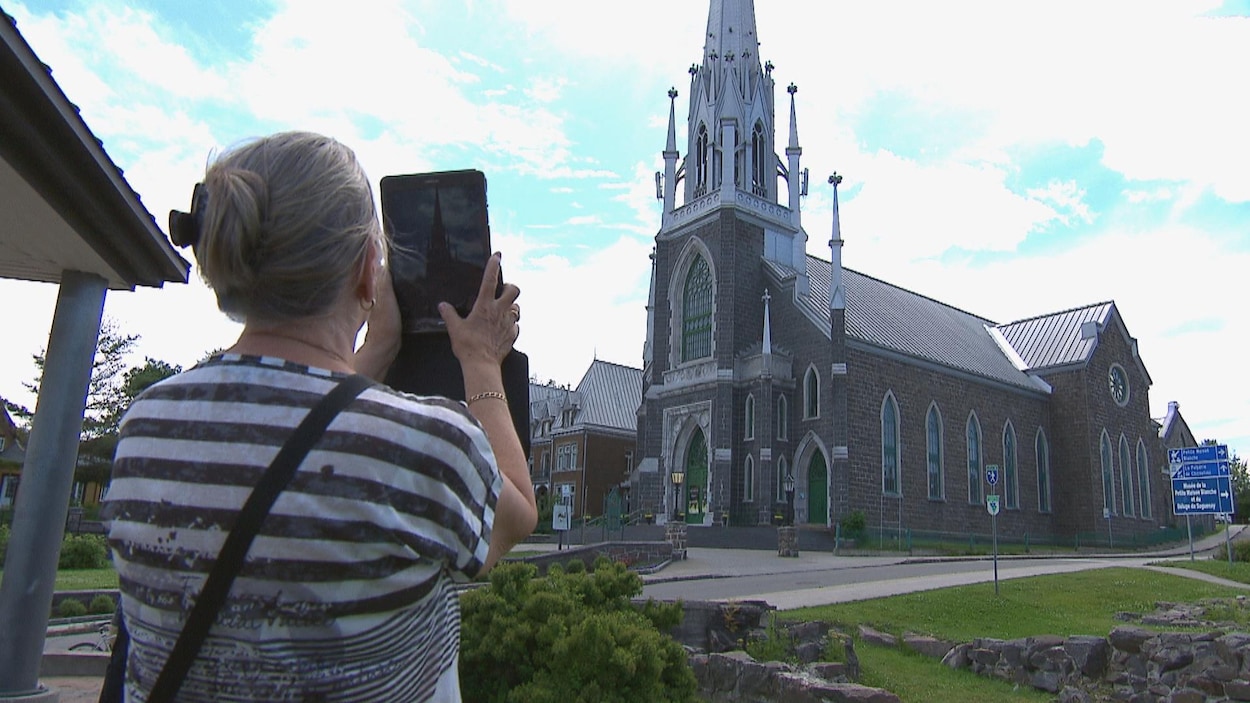 Une femme photographie une église.