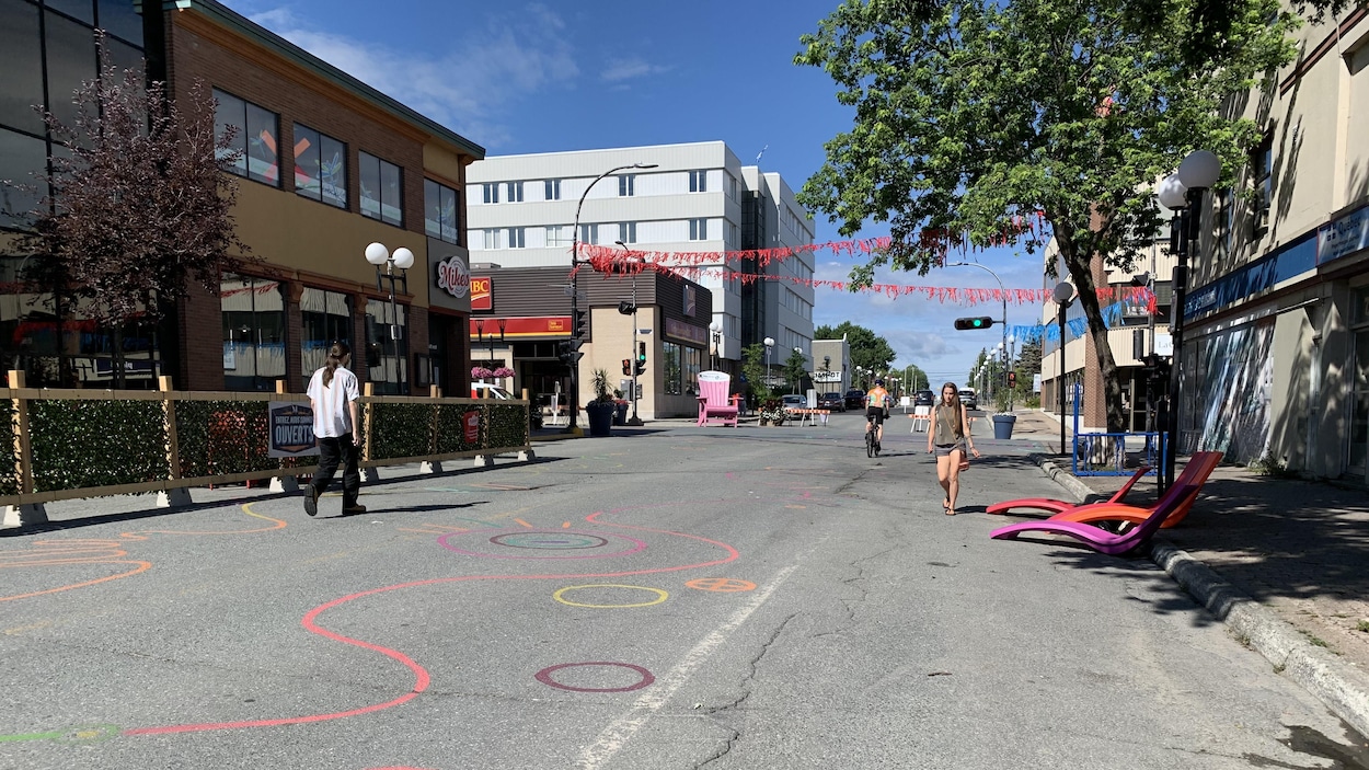 Des passants marchent sur la rue Perreault, décorée.