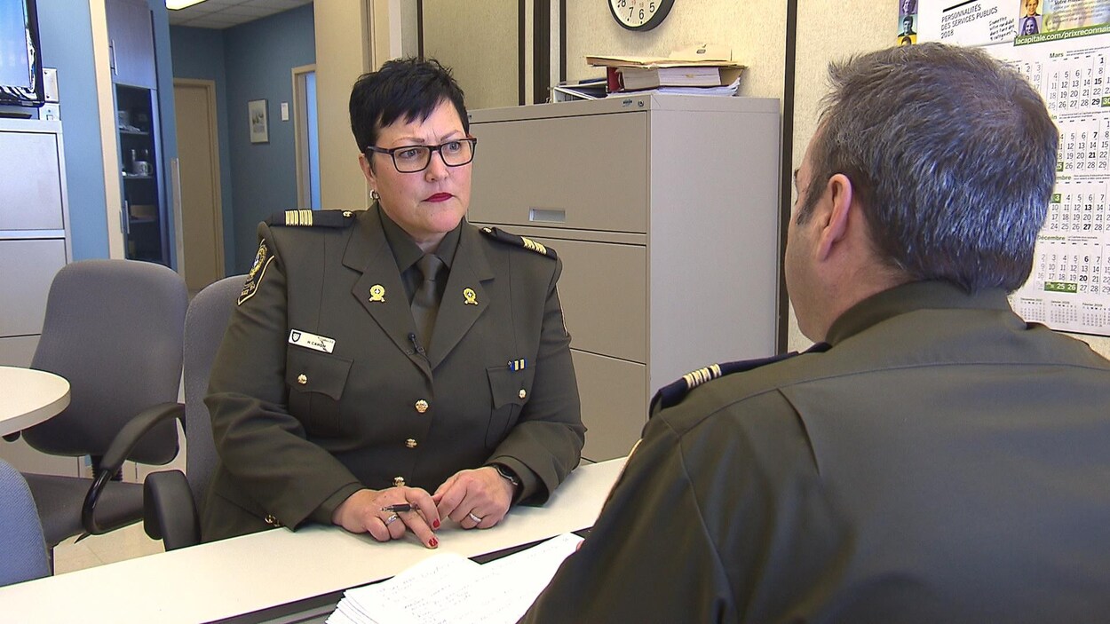 Une femme en habit de police écoute un policier à son bureau. Une femme en habit de police écoute un policier à son bureau.