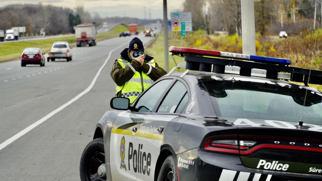 Un policier sur le bord de l'autoroute tient un radar.