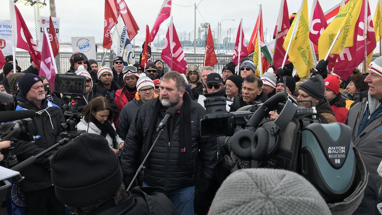 Un membre du syndicat d'Unifor parle au micro devant plusieurs de ses collègues.