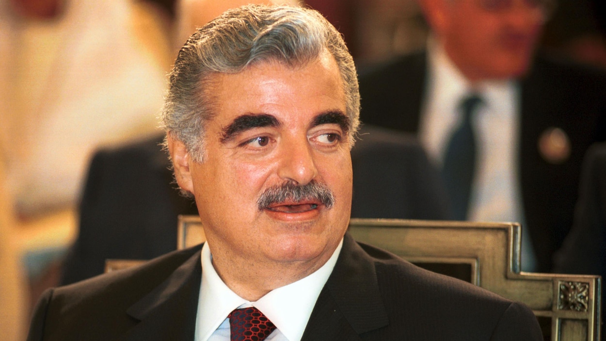 Rafic Hariri assis sur une chaise tourne la tête pour regarder à gauche.