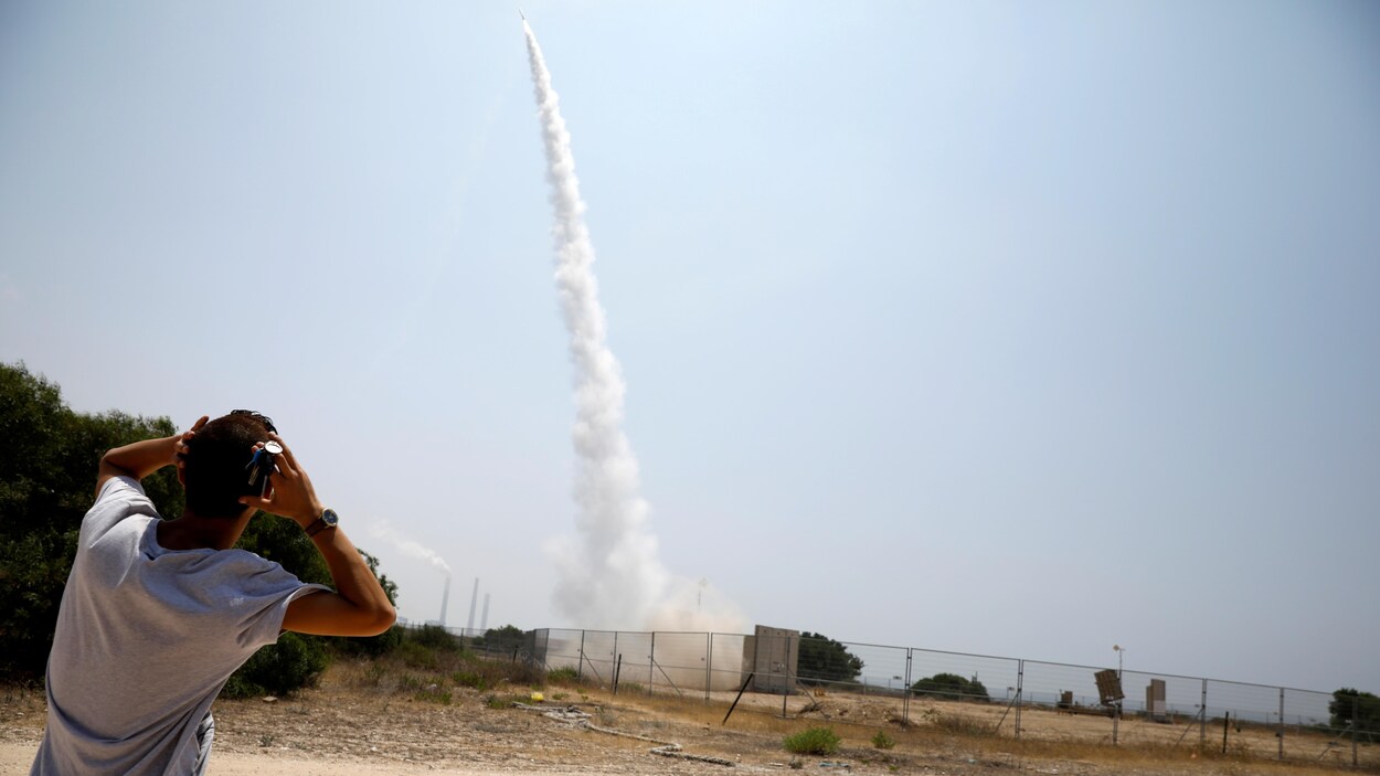Un israélien regarde un lanceur Iron Dome s'envoler en se mettant les mains sur la tête.