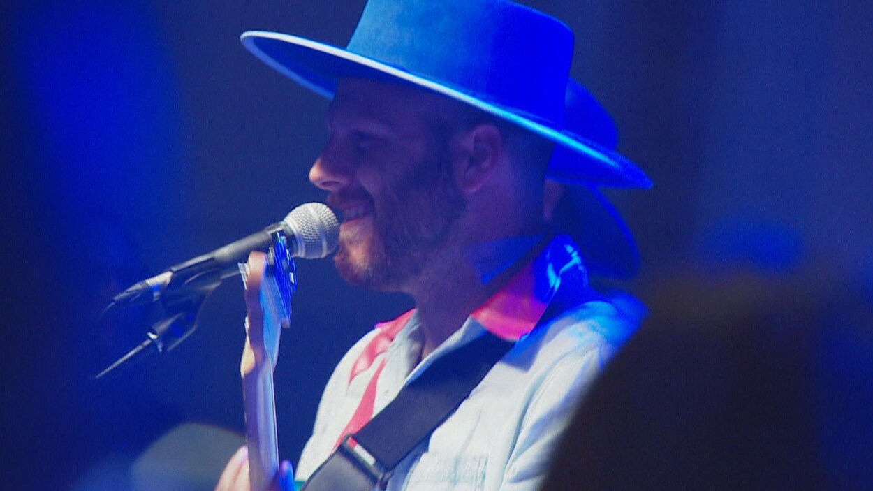Le chanteur du groupe Bleu Jeans Bleu sur scène, en train de chanter.