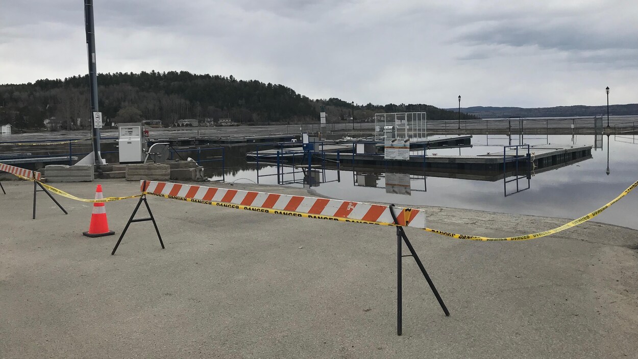 Des barrières et un ruban Danger sont posés dans une marina pour en empêcher l'accès.