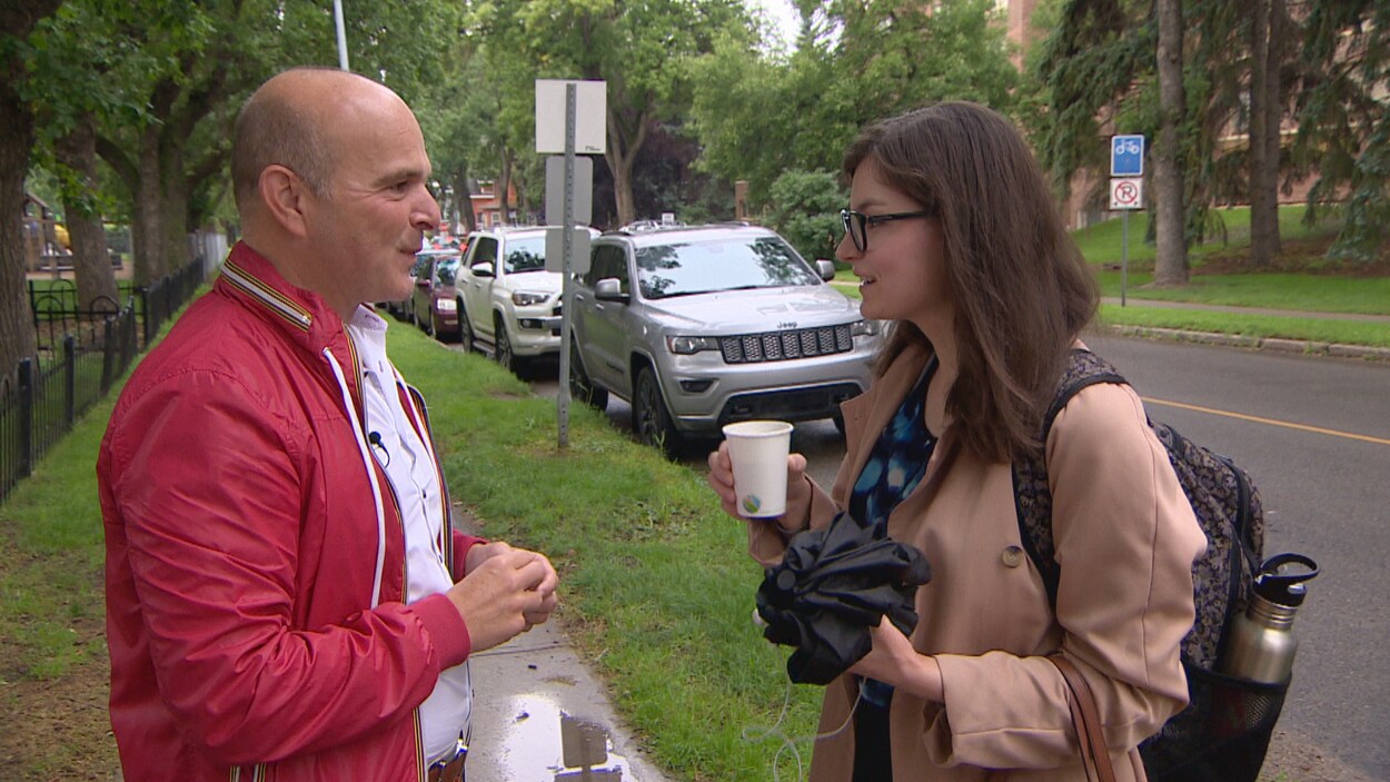 Randy Boisonneault discute avec une citoyenne qui tient un café dans ses mains.