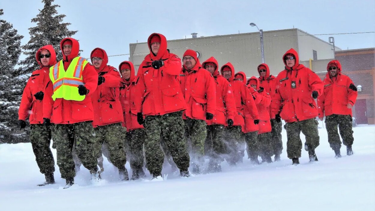 Un groupe habillé en rouge court en peloton dans la neige.