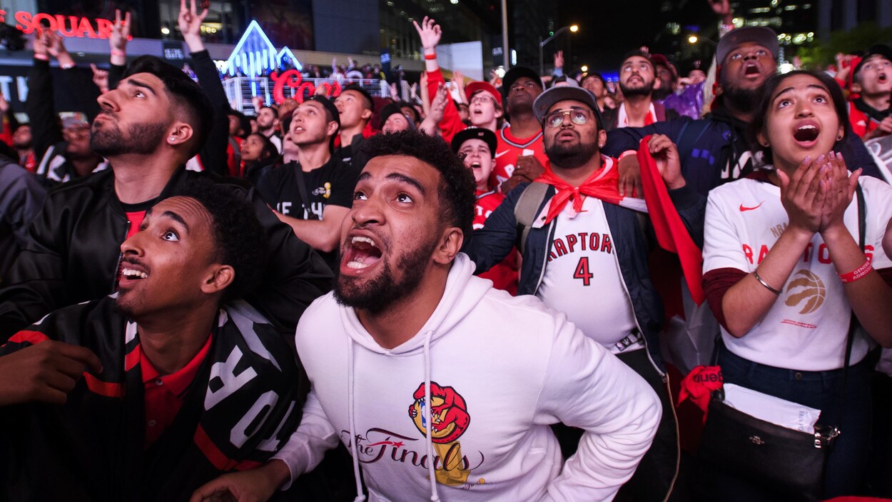 Des partisans torontois réunis à l'extérieur la nuit réagissent à la victoire des Raptors.