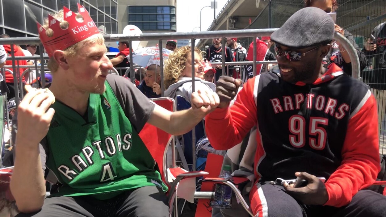 Deux hommes se font un « fistbump » dans une file d'attente.