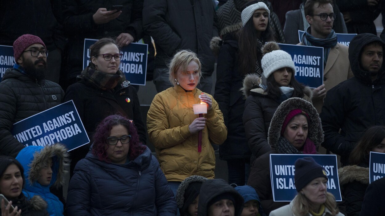 Des gens tiennent une bougie ou une affiche sur laquelle on peut lire : « Unis contre l'islamophobie ».