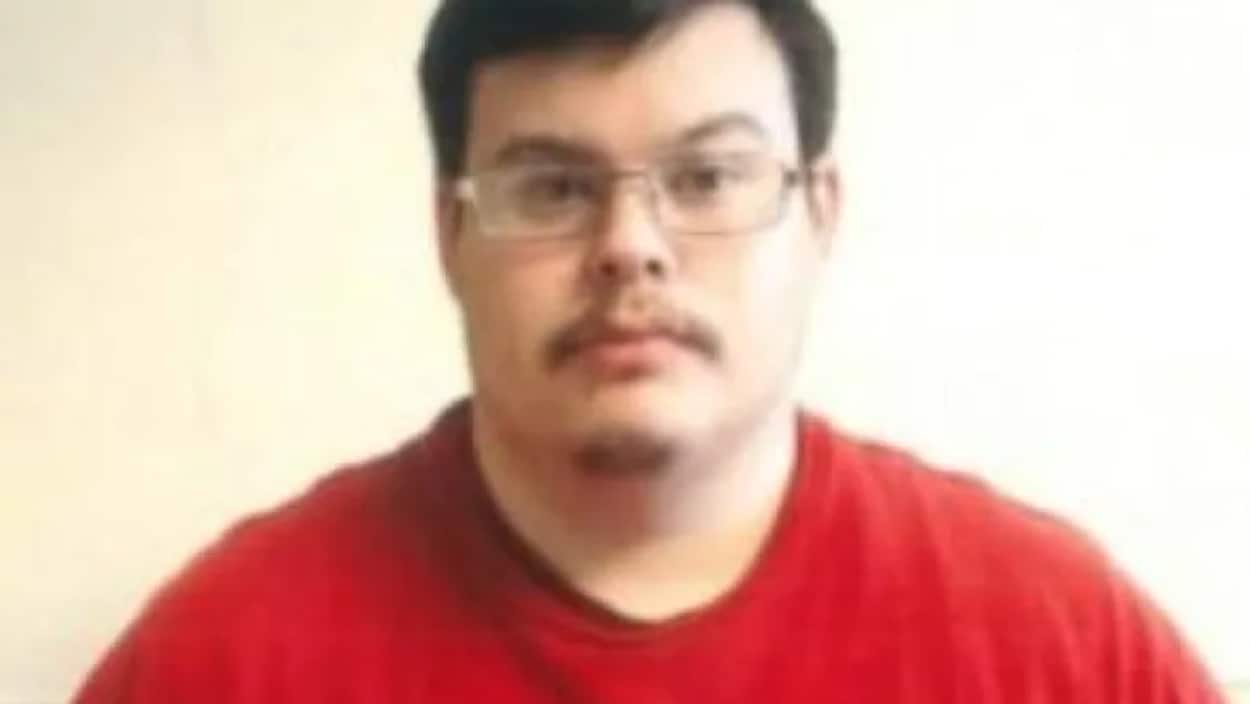 Un homme avec des lunettes et un chandail rouge.