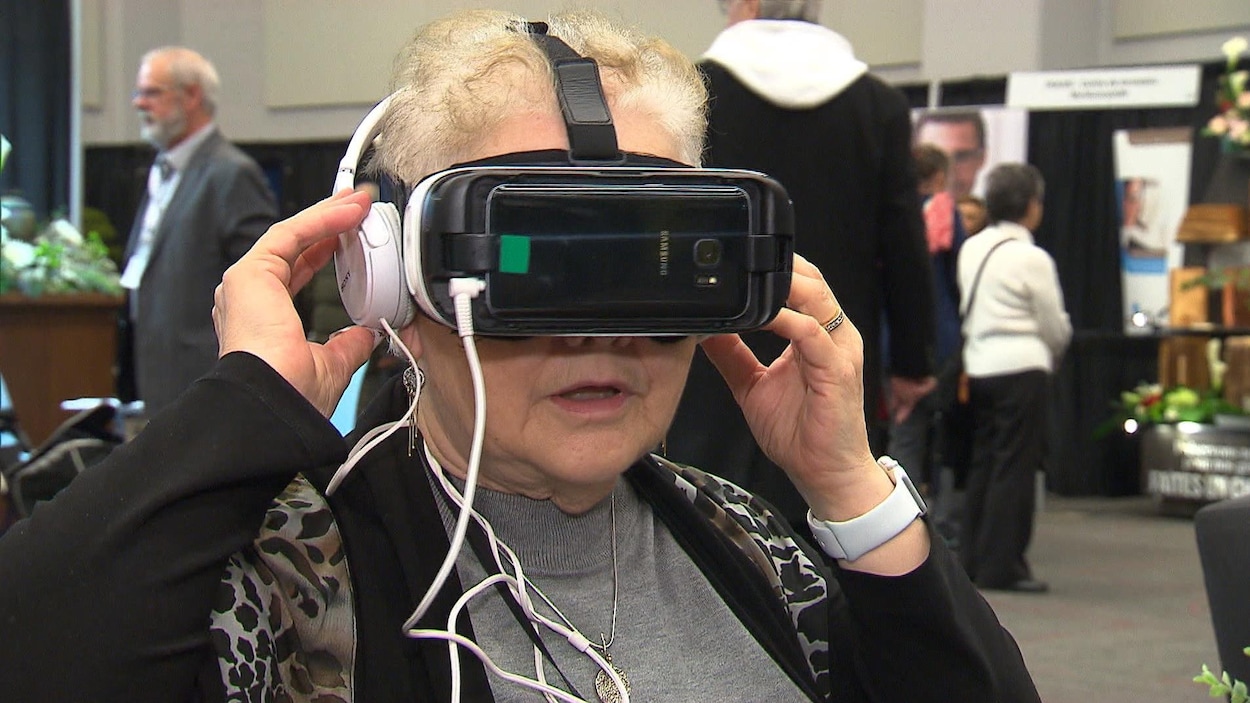 Une dame porte un casque de réalité virtuelle sur la tête, avec des écouteurs.