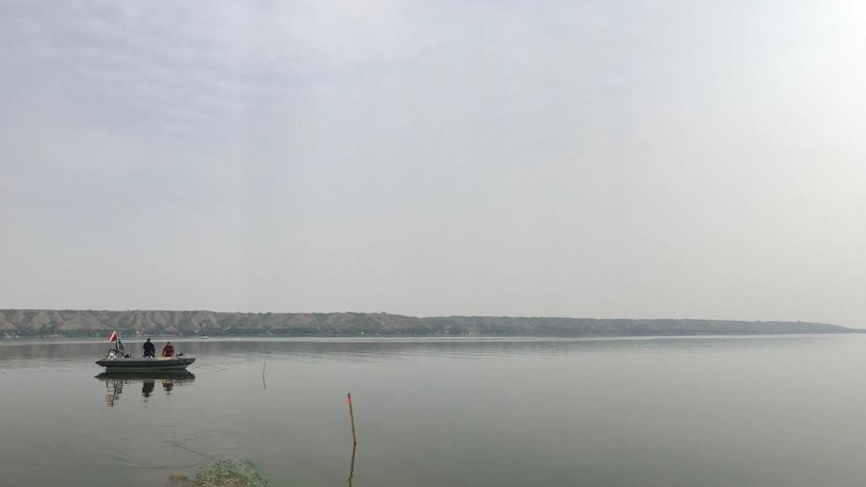 Un petit bateau sur un lac aux eaux calmes, contenant deux personnes. Un petit bateau sur un lac aux eaux calmes, contenant deux personnes.