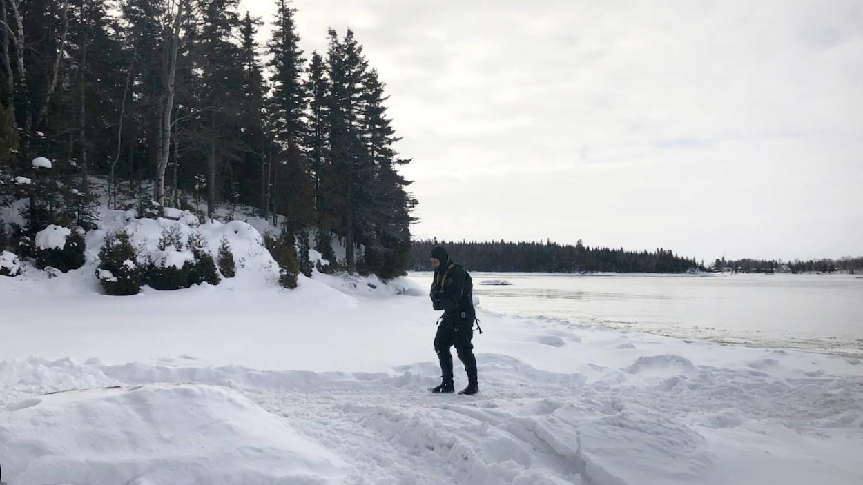 Un plongeur marche sur la neige en bordure du lac Saint-Jean.
