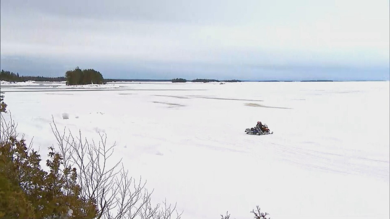 Deux motoneiges sur un lac gelé.
