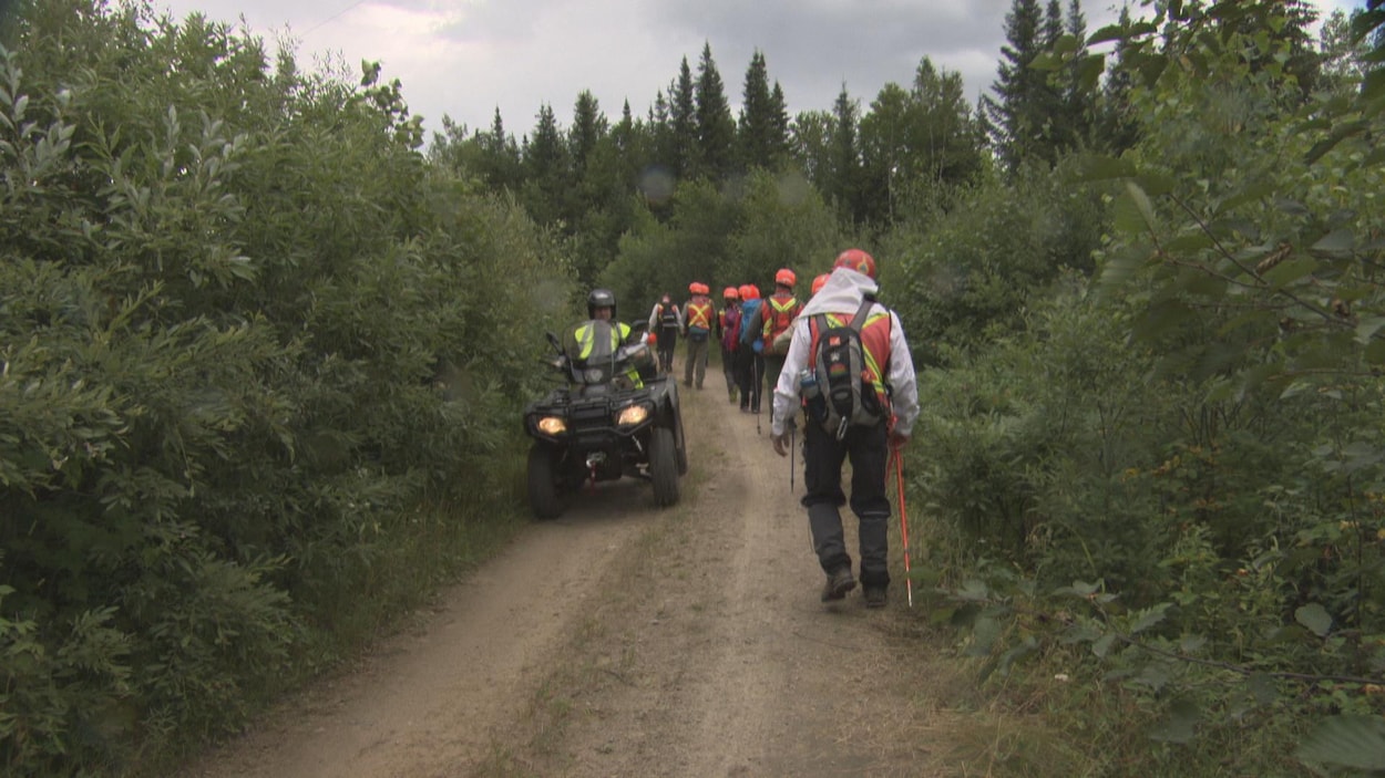 Des marcheurs et un agent en véhicule tout-terrain dans un sentier boisé lundi.