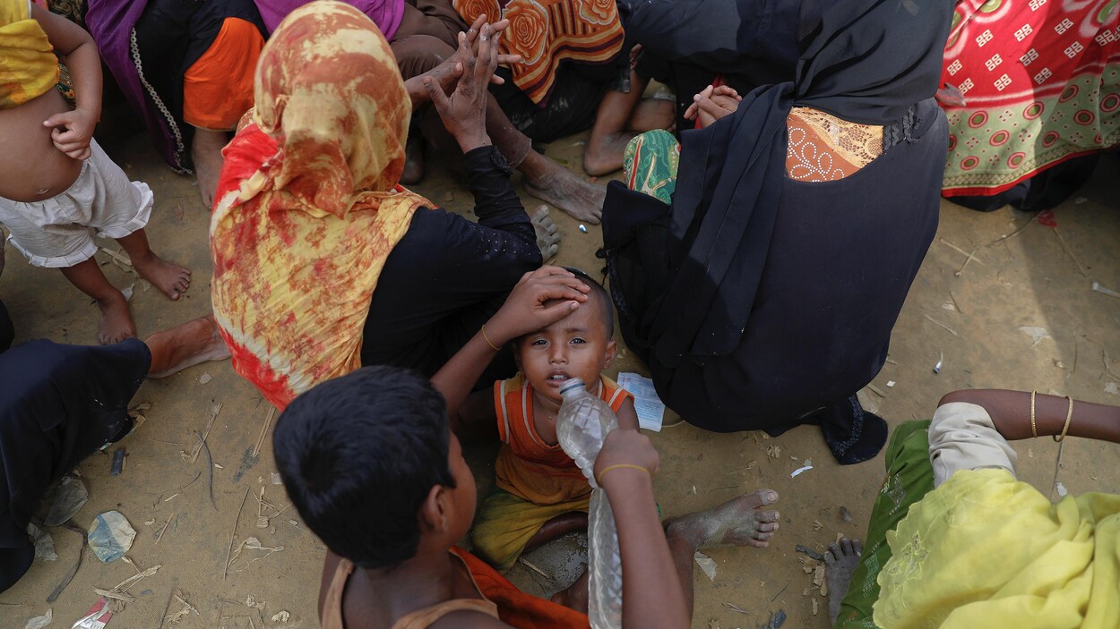 Un garçon donne à boire à son jeune frère dans l'attente d'une distribution d'aide humanitaire dans un camp du Bangladesh. Un garçon donne à boire à son jeune frère dans l'attente d'une distribution d'aide humanitaire dans un camp du Bangladesh.