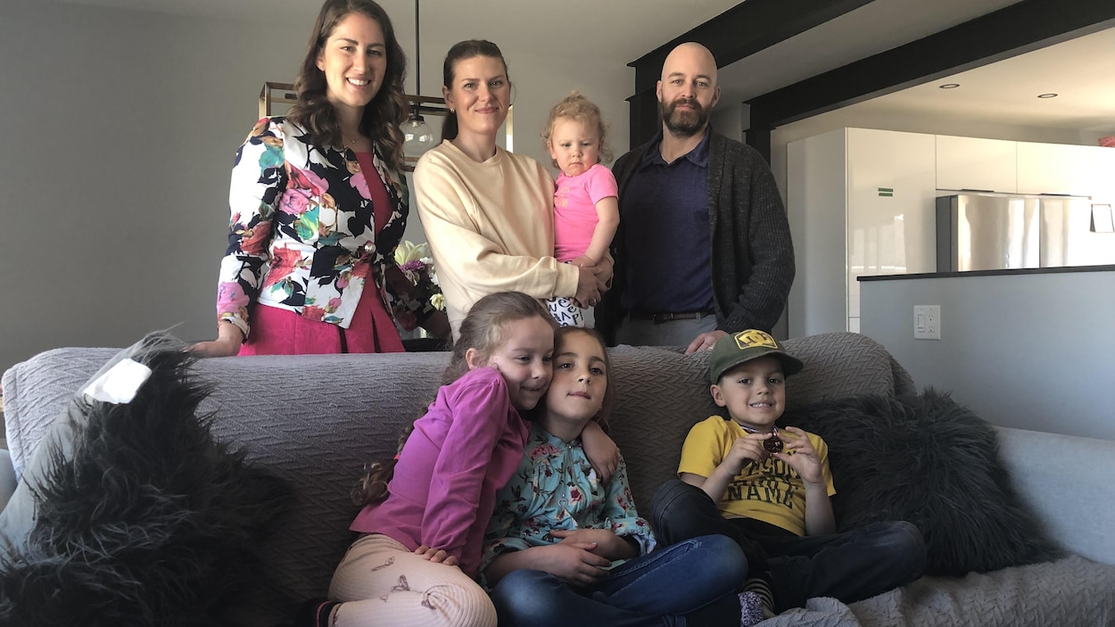 Trois adultes et un enfant sont derrière un divan, où trois enfants sont assis.