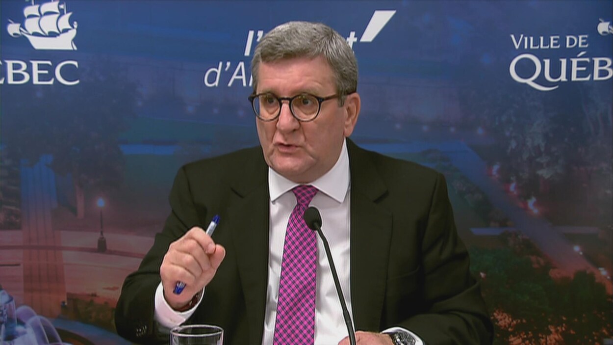 Régis Labeaume est assis à une table avec un micro. Régis Labeaume est assis à une table avec un micro.