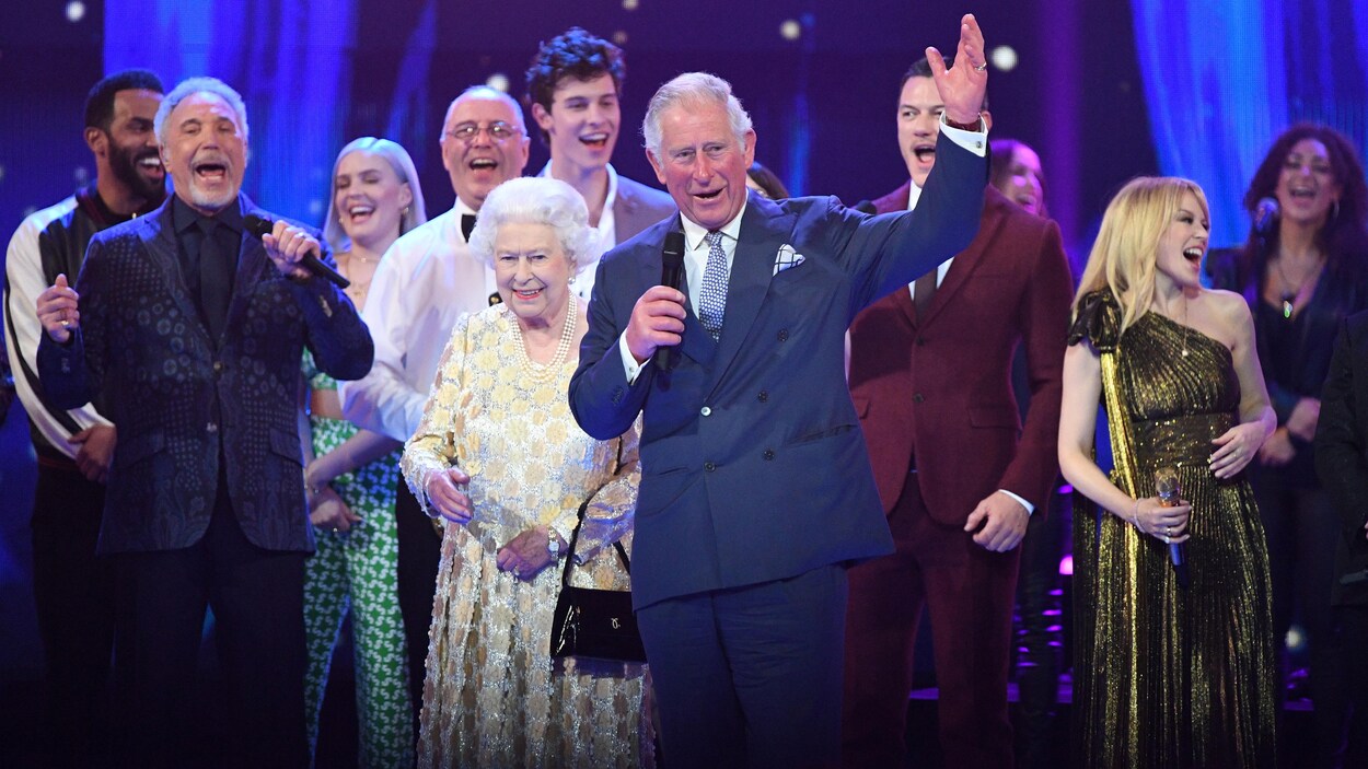 La reine Élisabeth II, sur scène, entourée de son fils Charles et de plusieurs artistes, dont Tom Jones, Shawn Mendes et Kylie Minogue. La reine Élisabeth II, sur scène, entourée de son fils Charles et de plusieurs artistes, dont Tom Jones, Shawn Mendes et Kylie Minogue.