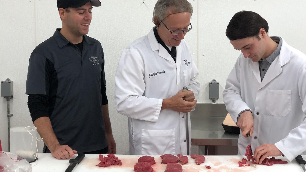 Jean-Yves Desmeules et deux étudiants en train de couper de la viande.
