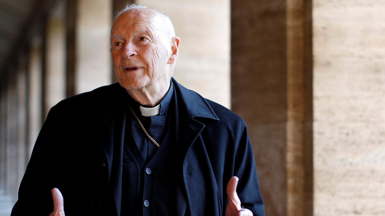 Un vieil homme portant l'habit d'un cardinal dans un corridor.