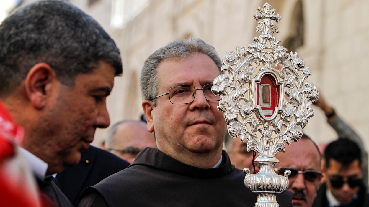 Un religieux au début d'une procession tient la relique devant lui.
