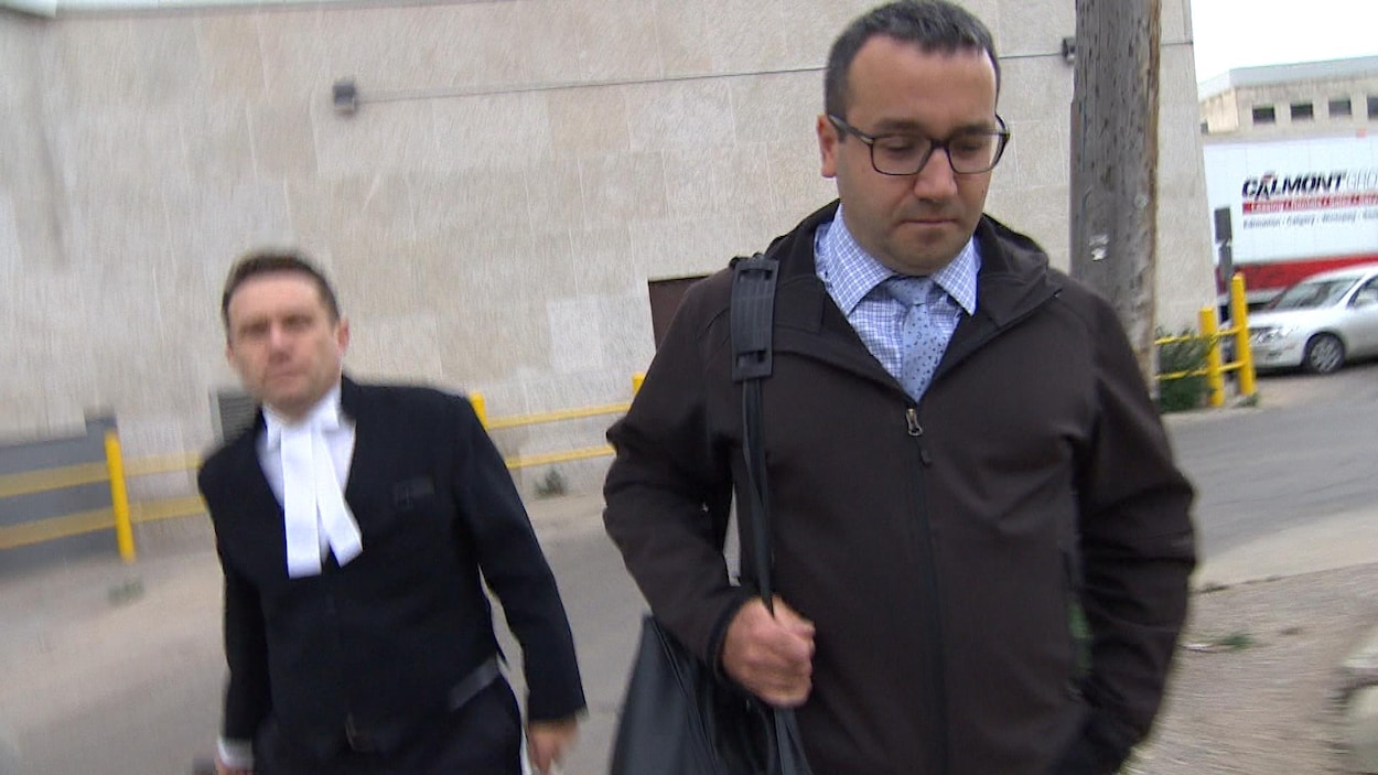 Rémi Dallaire marche, en regardant par terre, son avocat à sa droite.