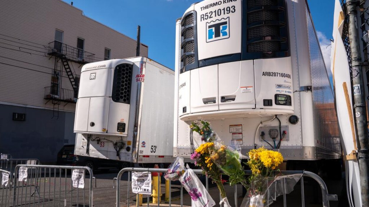 Des fleurs sont accrochées à la barrière près de deux camions frigorifiques.