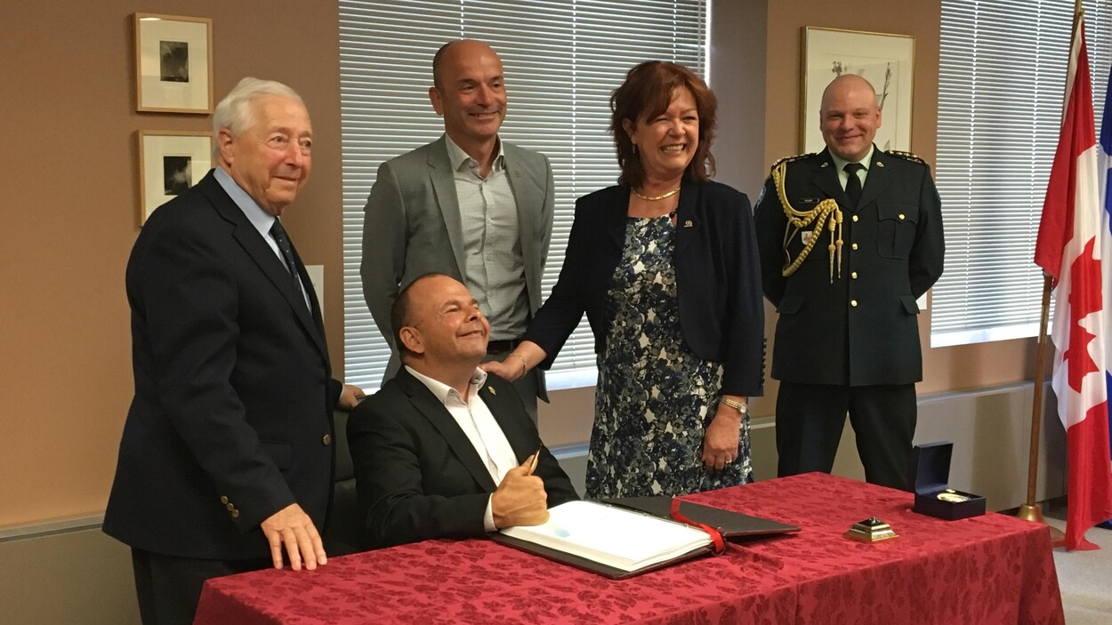 Cinq personnes, dont J. Michel Doyon, Diane Dallaire et Rémy Mailloux, posent lors de sa signature du livre d'or.