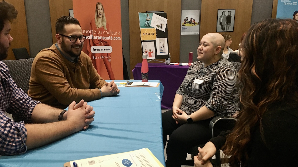 Deux hommes derrière une table discutent avec deux femmes.